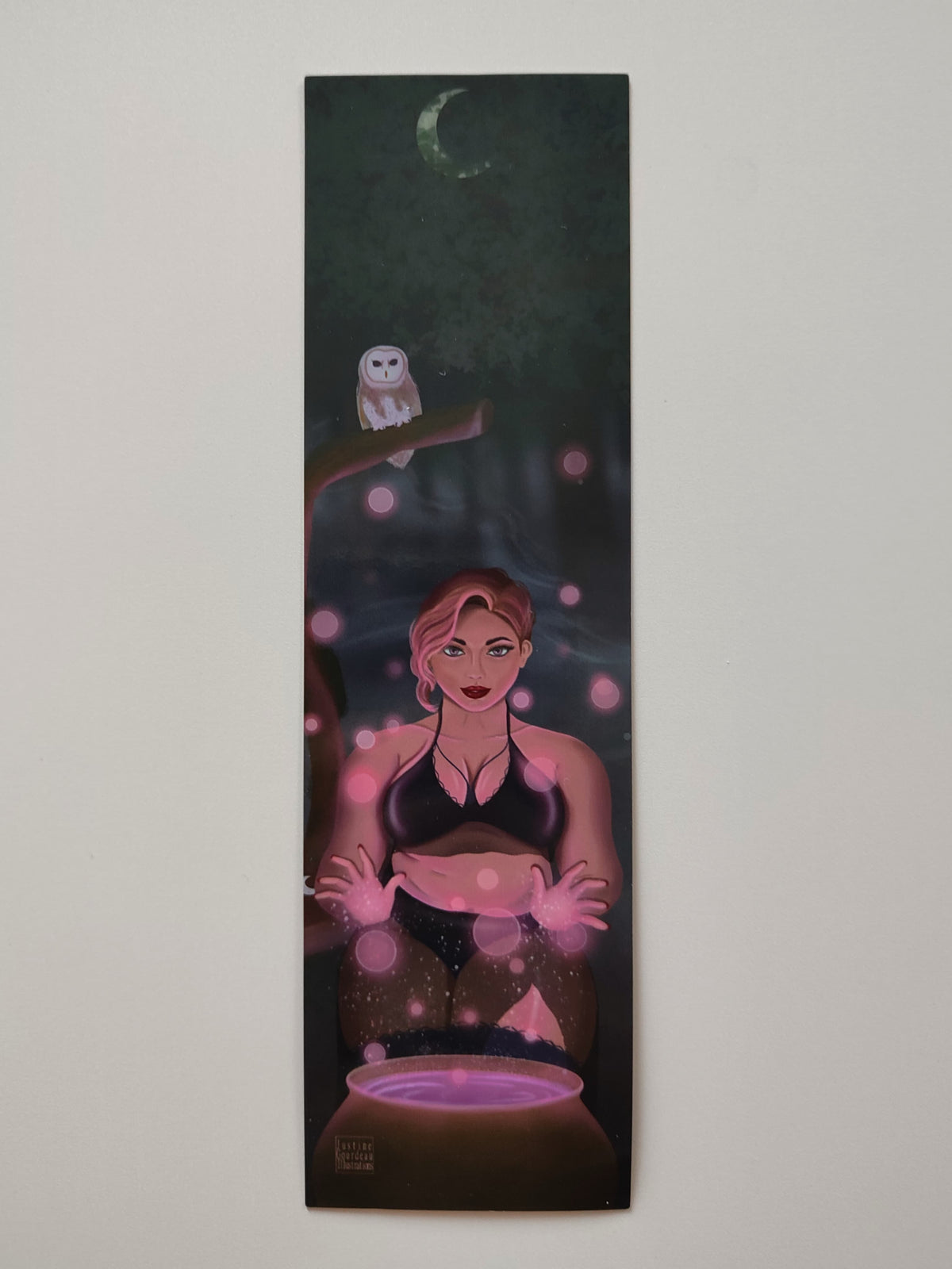 marque-pages illustré Stella, posé sur une fond blanc crème, montrant  une sorcière faisant de la magie rose devant une chaudron et en tenue sexy
