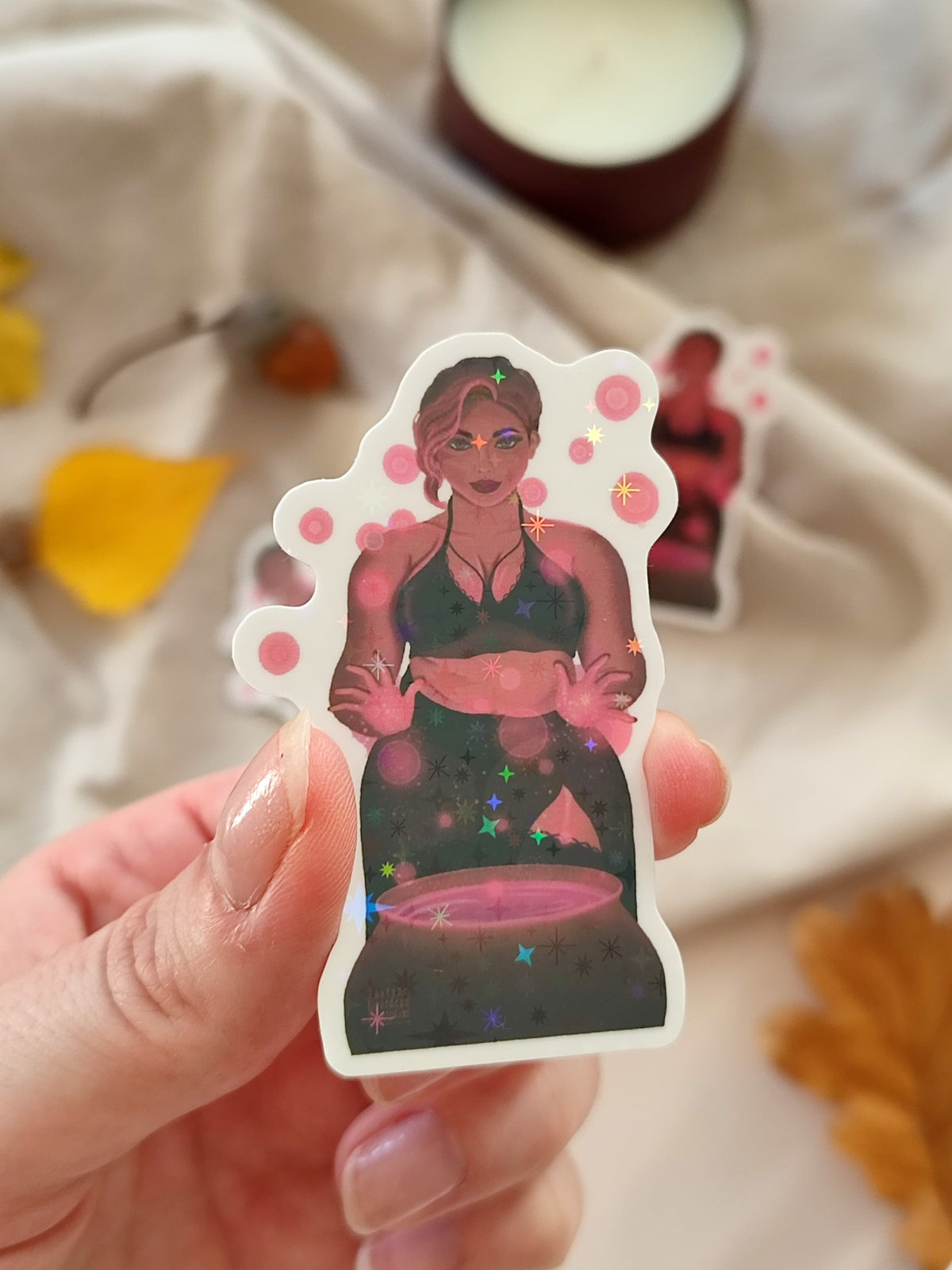 sticker holographique Stella représentant une socière au-dessus de son chaudron avec de la magie rose